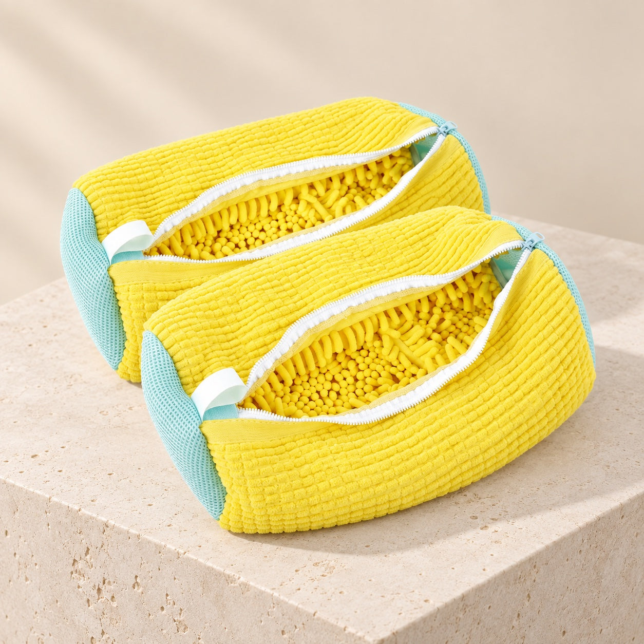 Two open yellow ScrubKix shoe wash bags displayed together on a stone surface